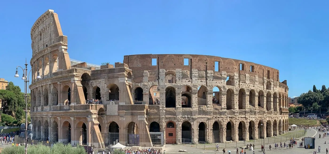 The Colosseum's ruined outer wall, with tiers of arches and visitors gathered at its entrances