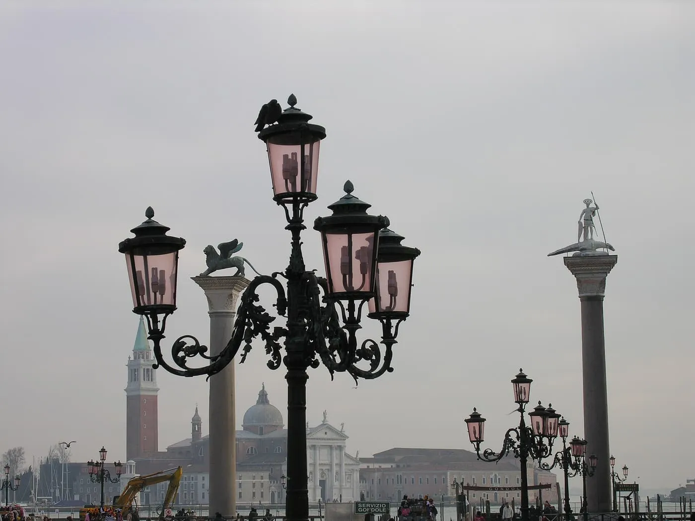 The column of the winged lion and the column of St Theodore beside a pink-glassed street lamp, with San Giorgio Maggiore across the water in haze