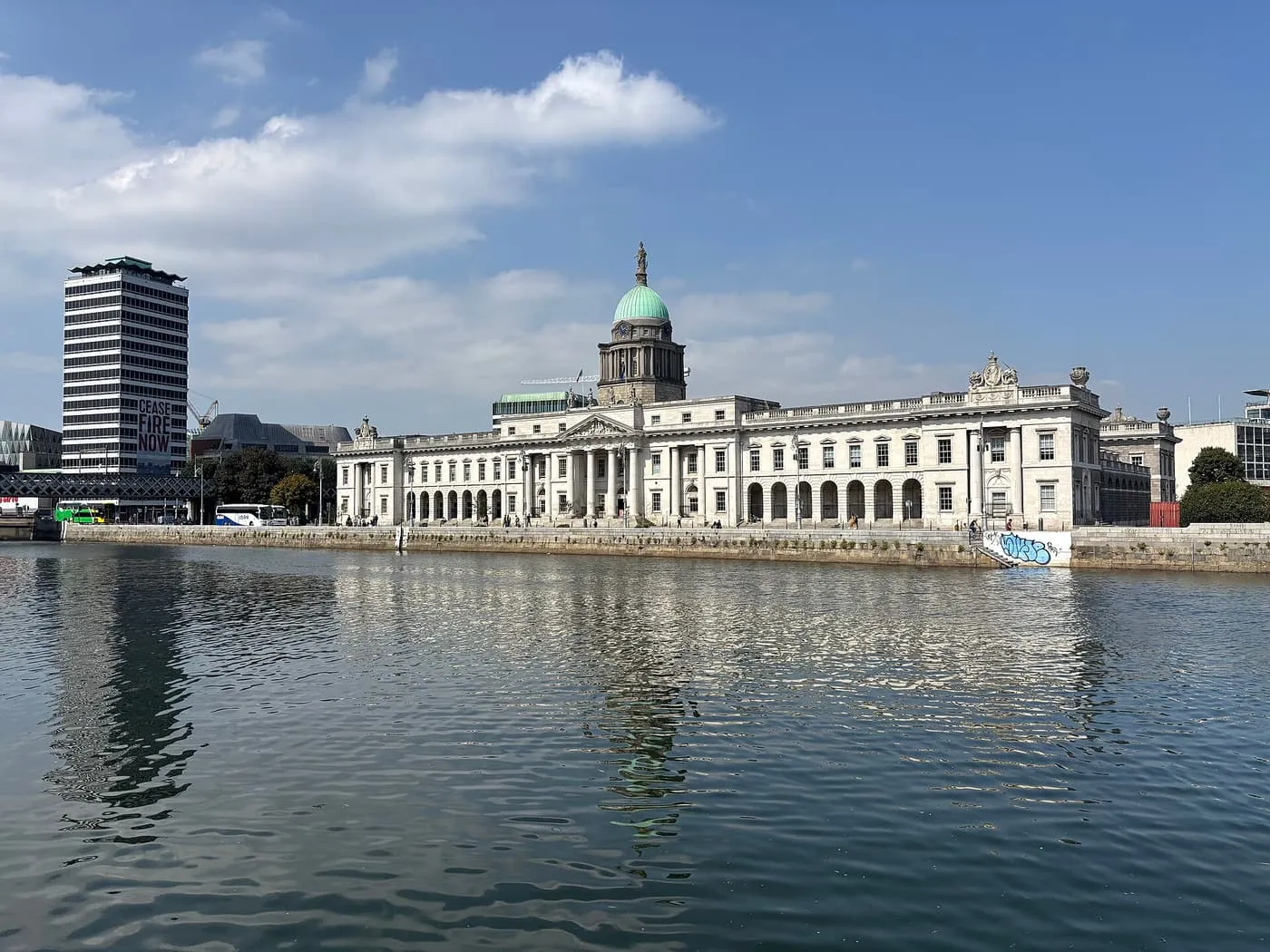 The long stone front of the Custom House with its green copper dome, seen across the River Liffey
