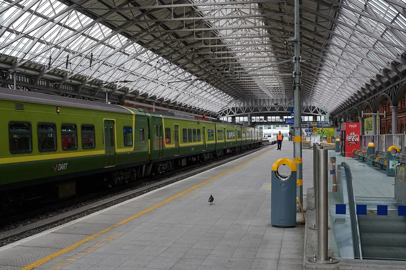A green DART train standing at a platform under the glazed iron roof of Dublin Pearse station