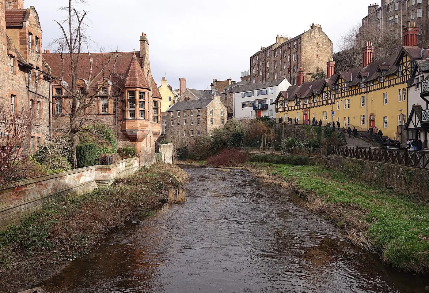 The Water of Leith running between stone houses and a long yellow terrace in Dean Village