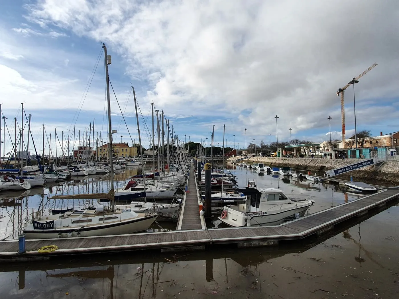 Sailing boats moored along wooden pontoons in the Doca do Bom Sucesso marina, with the dock's sign on the right