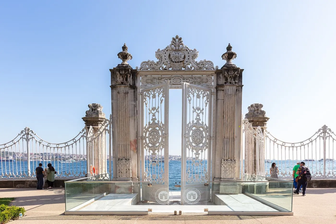 An ornate white wrought-iron gate at Dolmabahçe Palace opening onto the Bosphorus