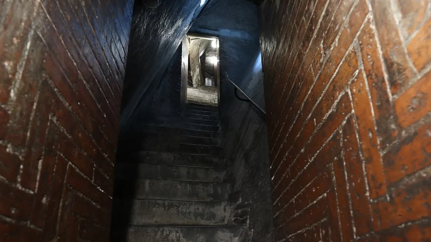 A narrow stone staircase climbing between walls of herringbone brick inside Brunelleschi's dome