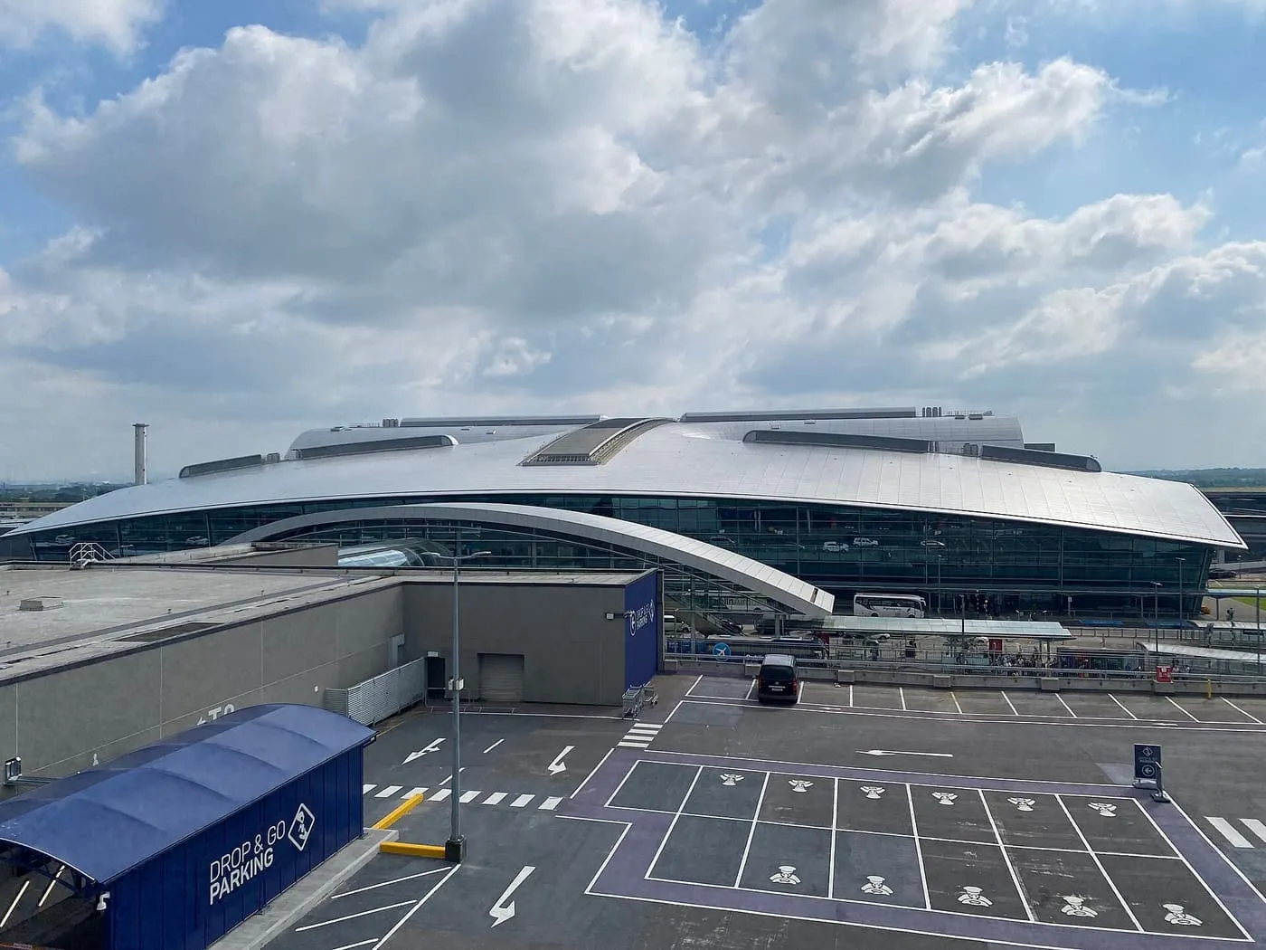 The curved silver roof of Dublin Airport Terminal 2 seen from a car park