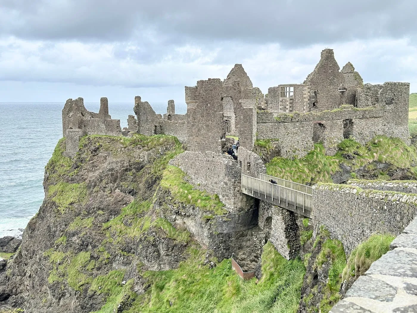 The ruins of Dunluce Castle on a sea cliff, reached by a short wooden footbridge
