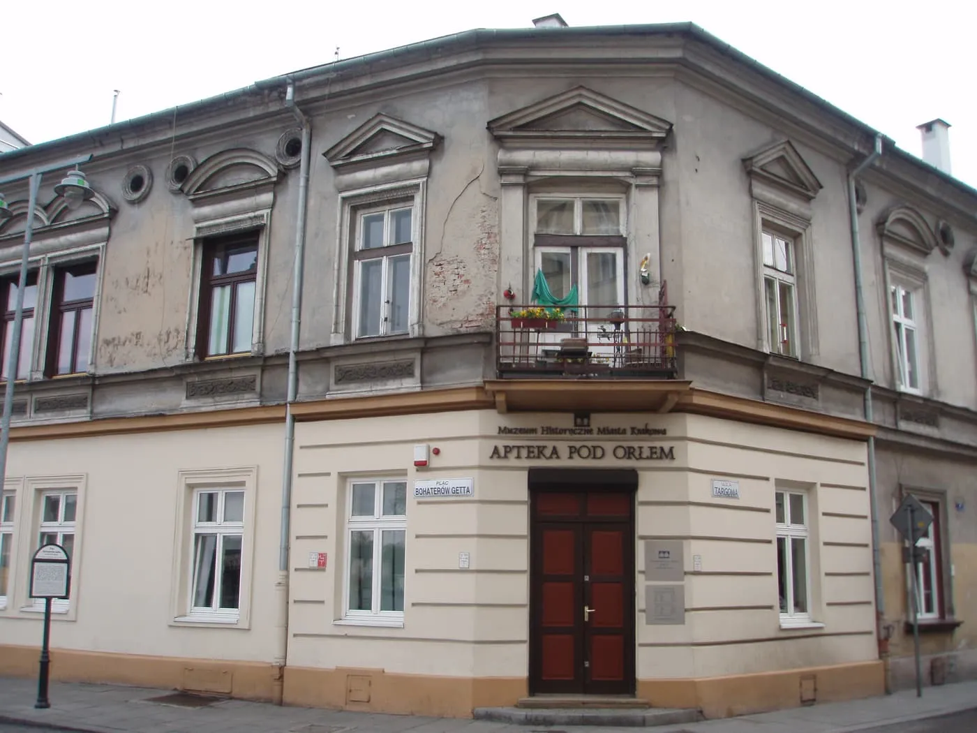 The Eagle Pharmacy on the corner of plac Bohaterów Getta, a pale two-storey building with the pharmacy sign above a red door