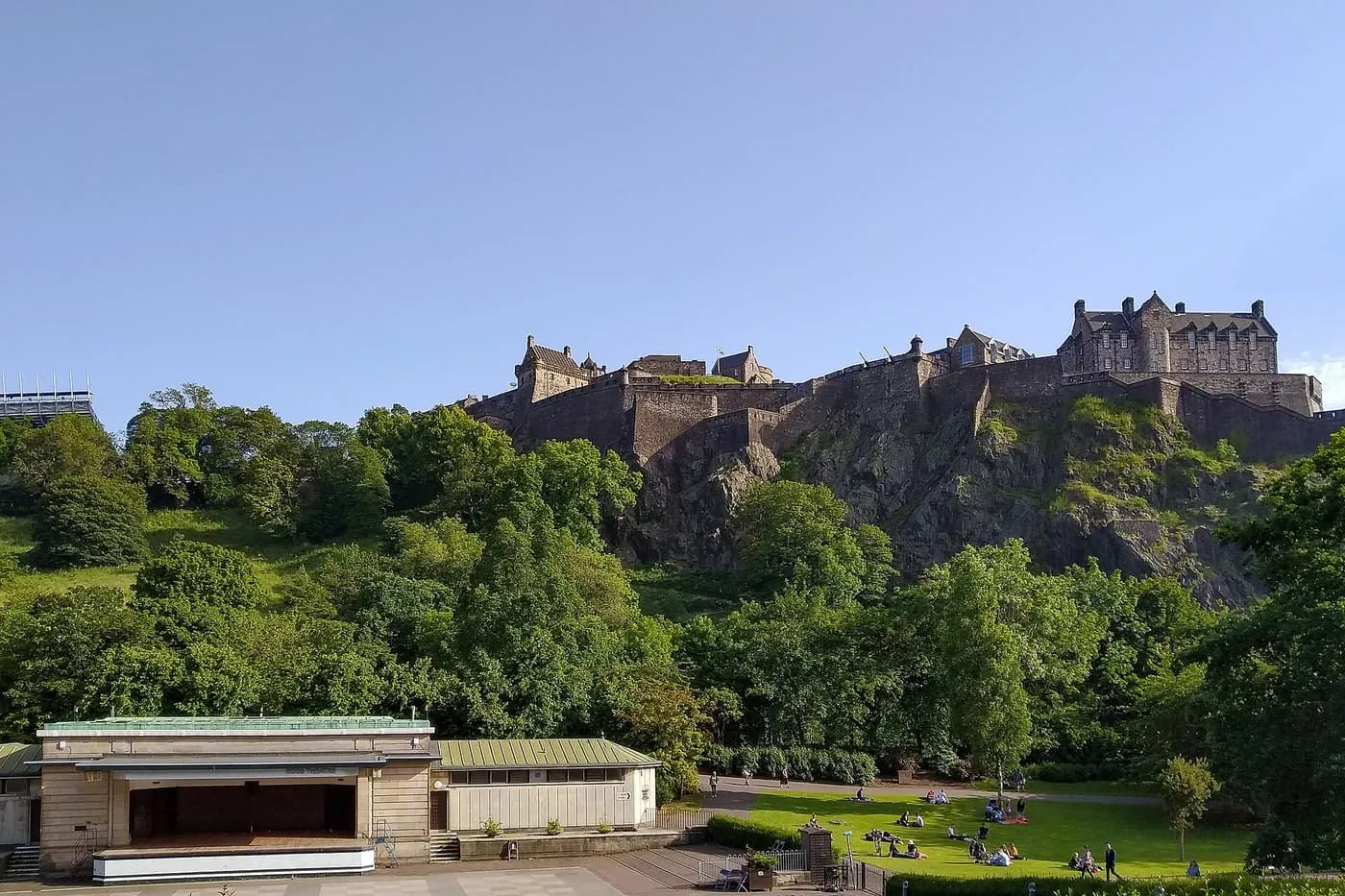 Edinburgh Castle on its rock above the trees of Princes Street Gardens, with the Ross Bandstand below