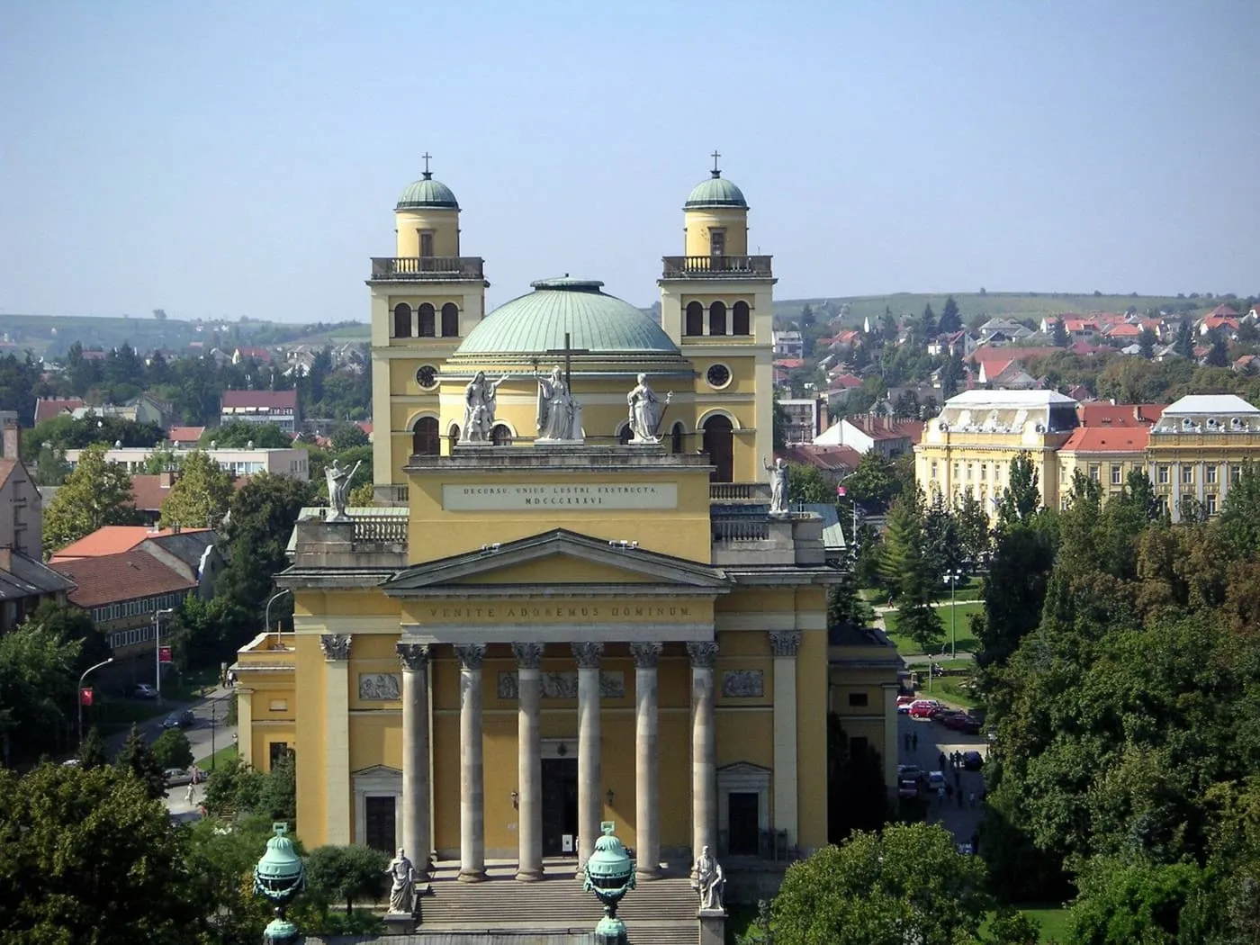 The yellow columned front and twin towers of Eger Basilica, with a green dome between them