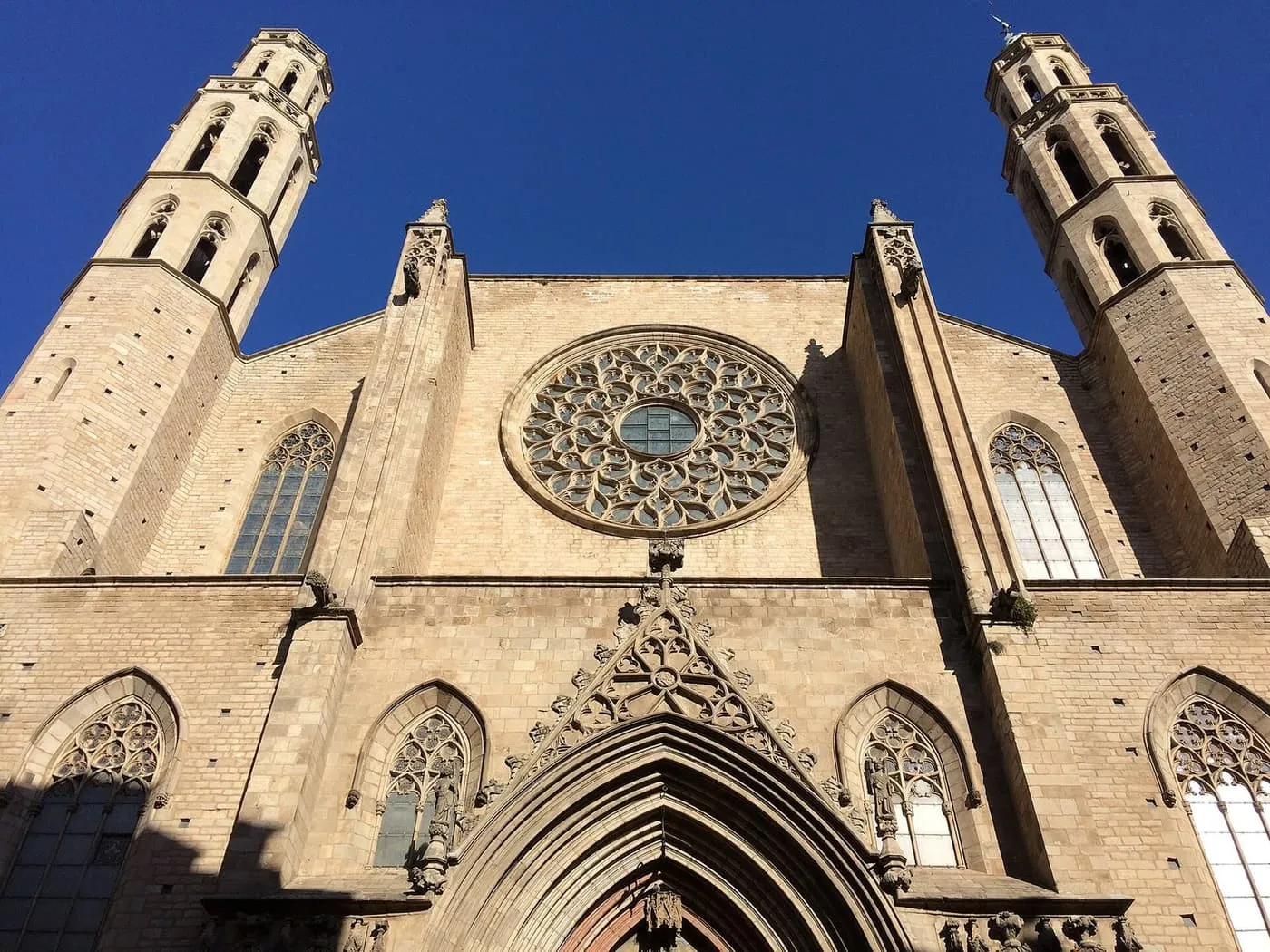 The Gothic west front of Santa Maria del Mar, with a rose window between two octagonal bell towers against a deep blue sky