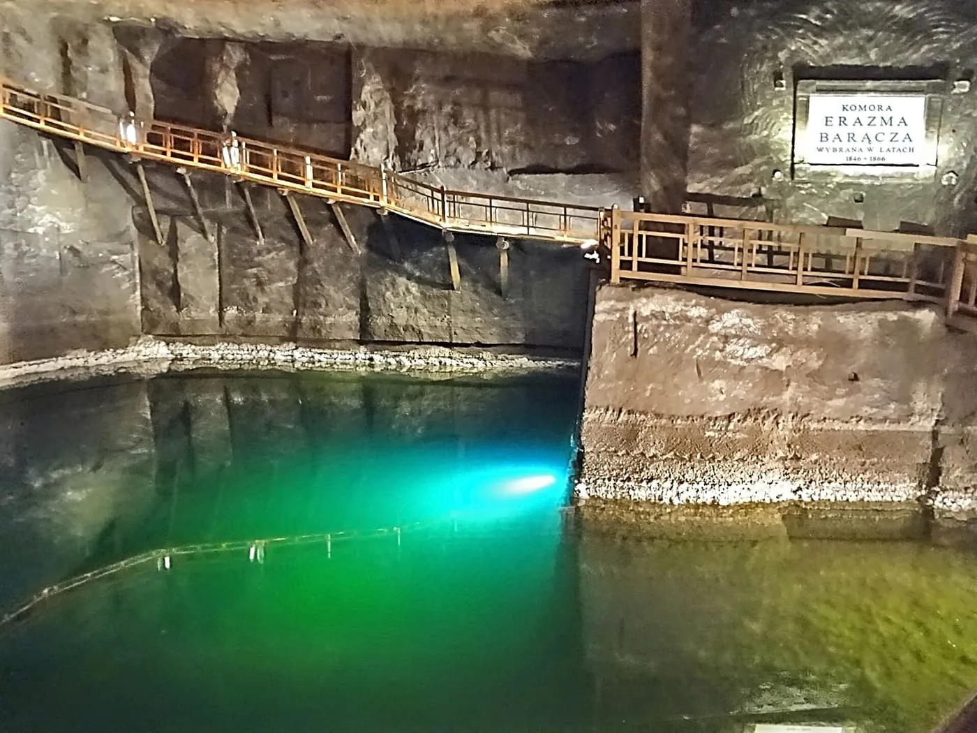 Green-lit brine lake below a wooden walkway in the Erazm Barącz chamber