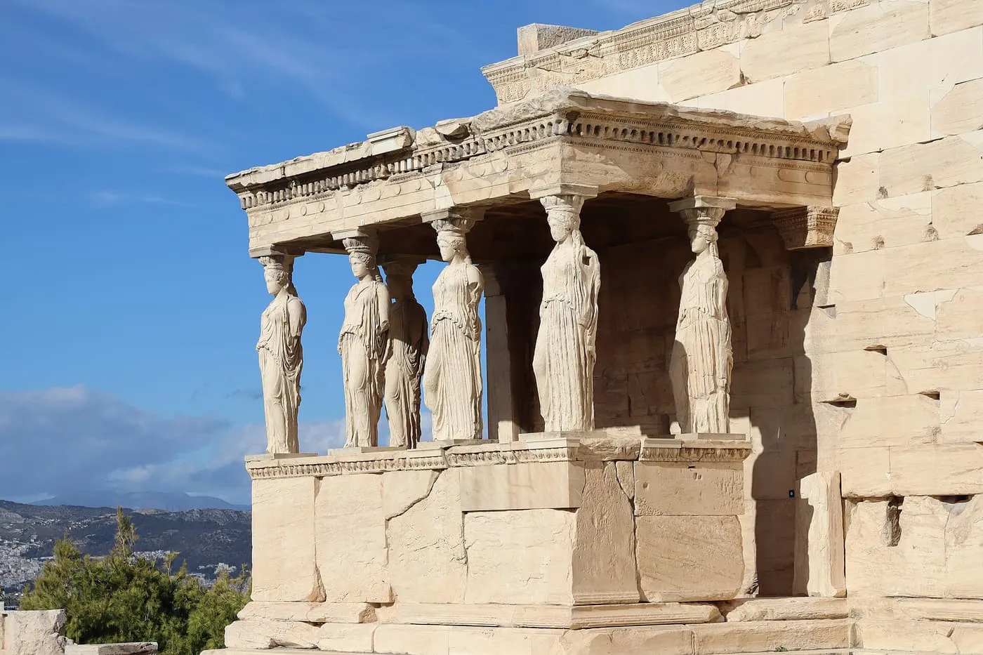The Porch of the Maidens on the Erechtheion, marble Caryatid figures standing on a high stone base in strong sun