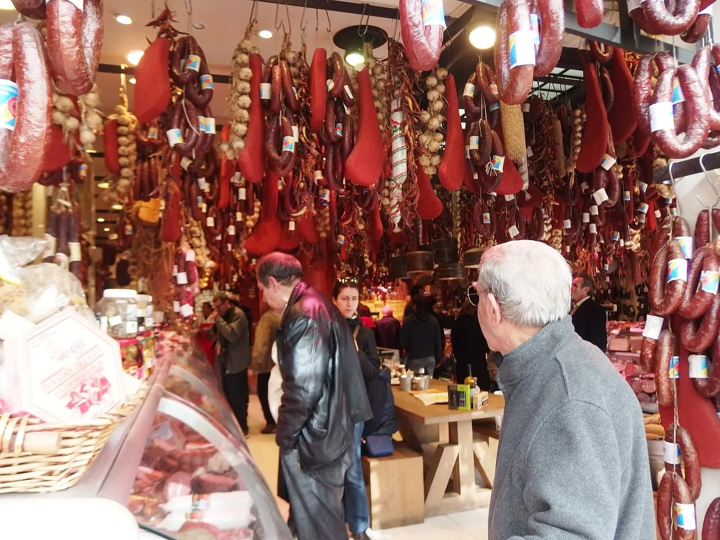 A delicatessen on Evripidou Street with cured sausages, red-coated pastourma, garlic and dried peppers hanging from the ceiling above the counter
