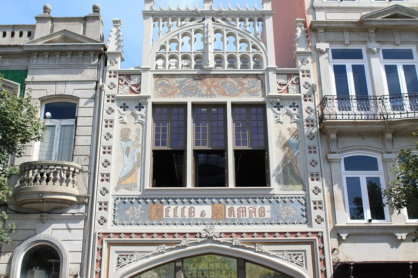 The neo-Gothic façade of Livraria Lello, with painted figures either side of the upper windows and the Lello & Irmão sign above the door