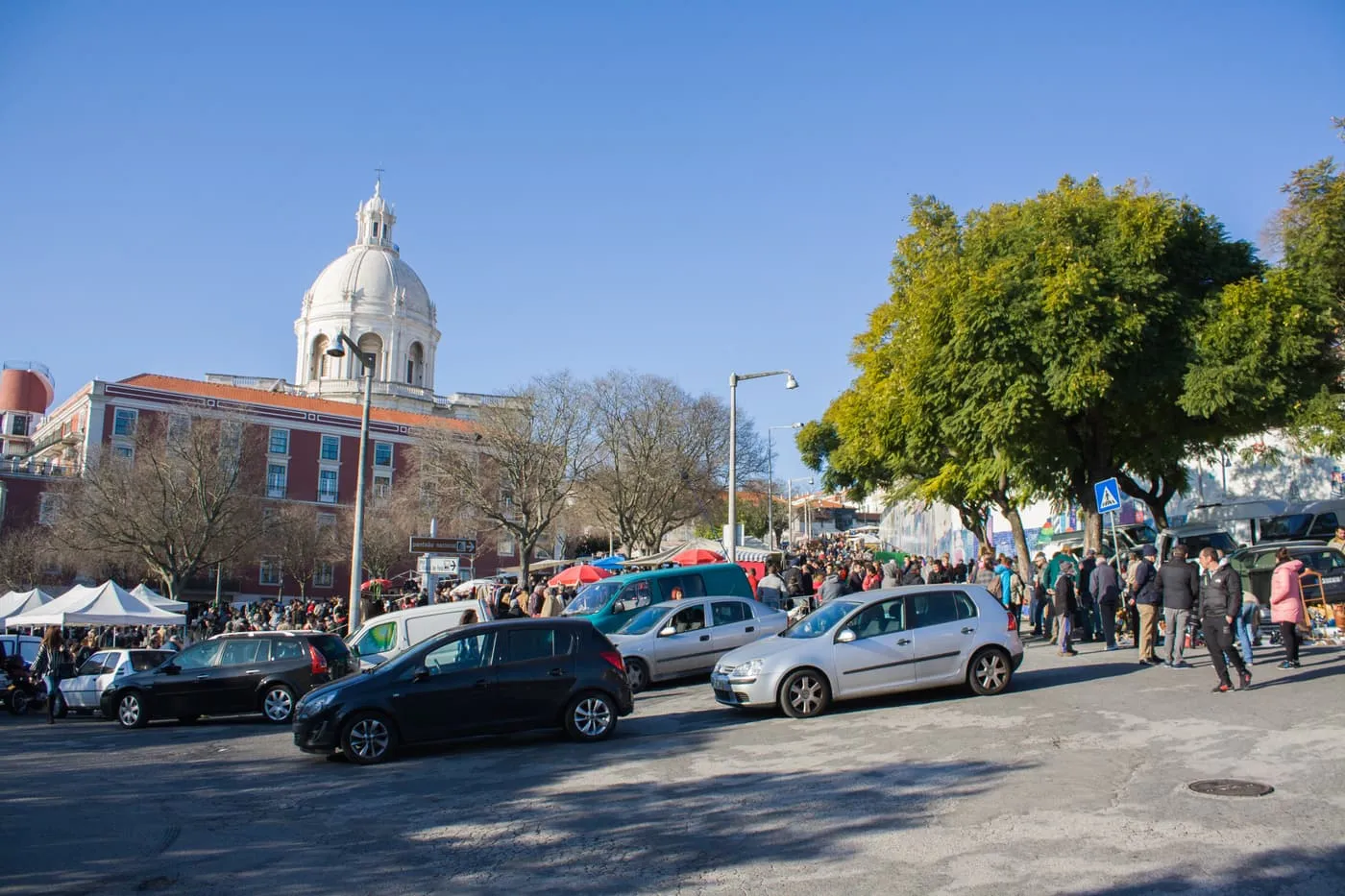 The Feira da Ladra in the Campo de Santa Clara, with market stalls and crowds in front of the white dome of the National Pantheon