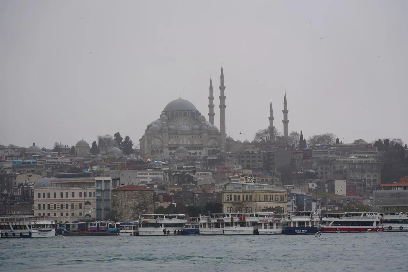 The Süleymaniye Mosque and its four minarets on its hill above a row of ferries and cruise boats along the Golden Horn