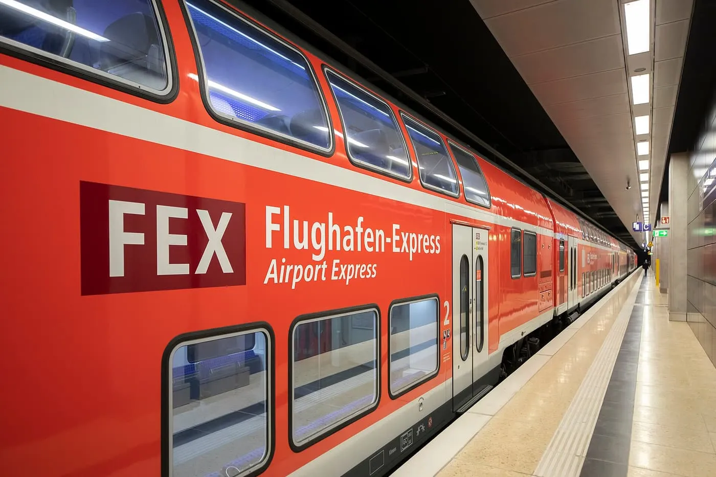 A red double-deck Flughafen-Express carriage at a platform in the underground station at BER