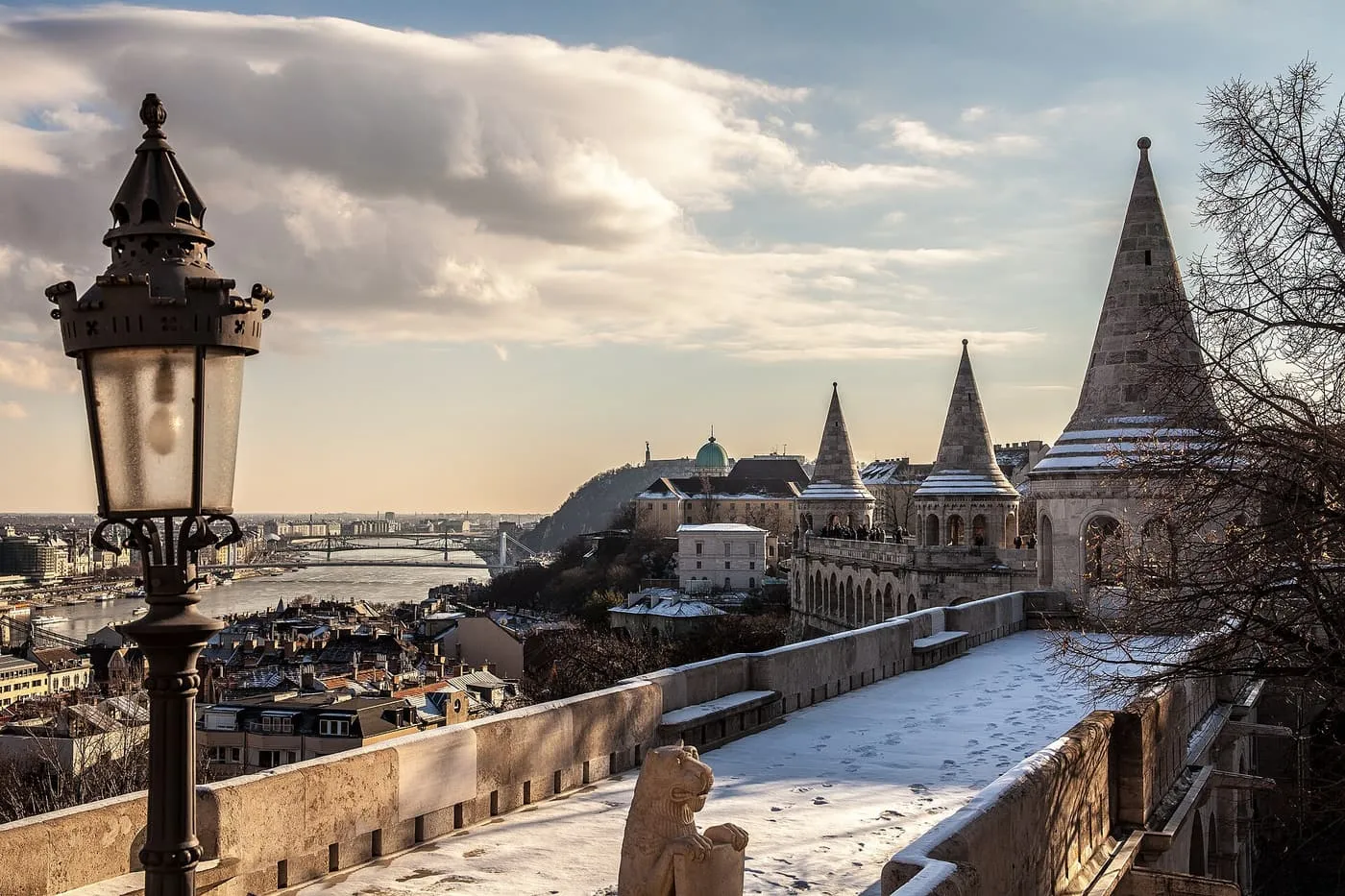 Snow on the walkway and cone roofs of Fisherman's Bastion, with the Danube and its bridges beyond