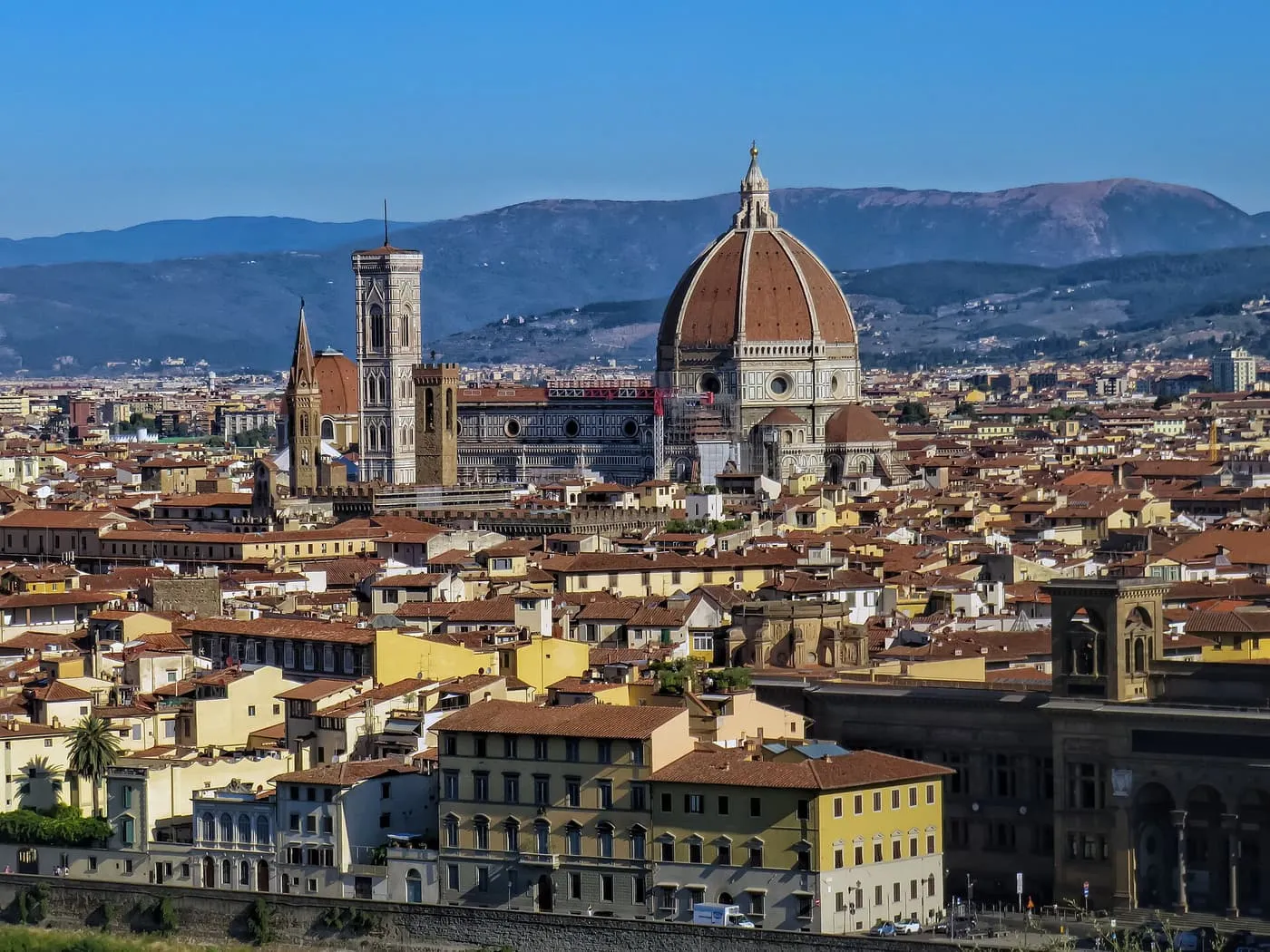 The dome of the Duomo and Giotto's Bell Tower above the terracotta roofs of Florence, with blue hills behind