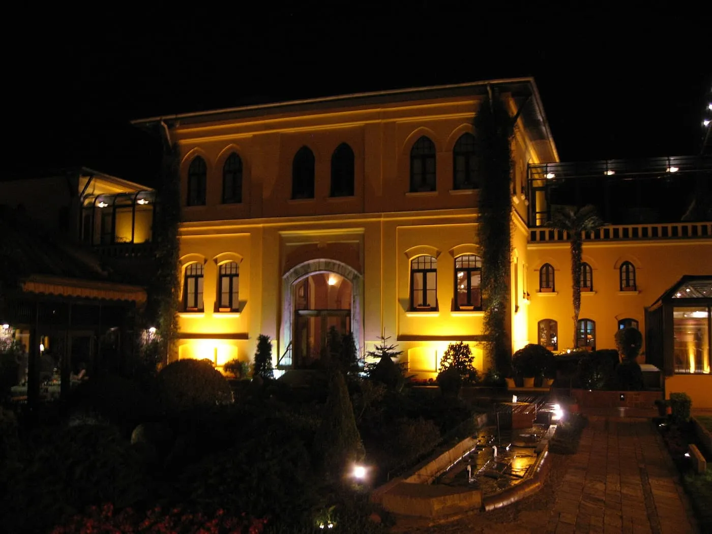 The lemon-yellow neoclassical facade of the Four Seasons Hotel in Sultanahmet, lit at night above its garden