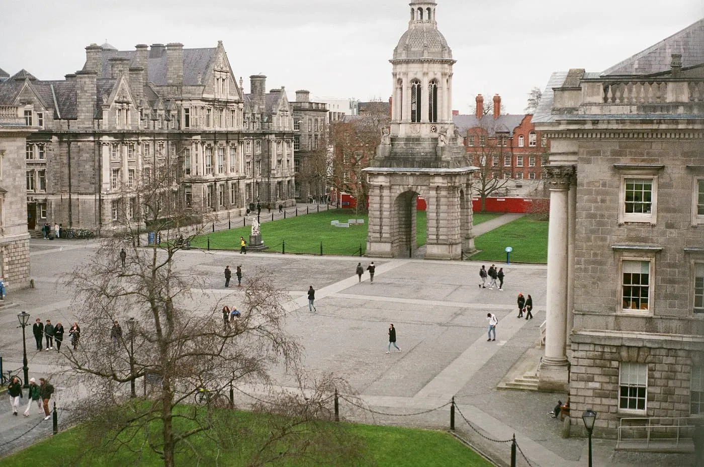 Front Square at Trinity College Dublin from above, with the Campanile and its arch standing on a lawn beside cobbled paving and stone buildings