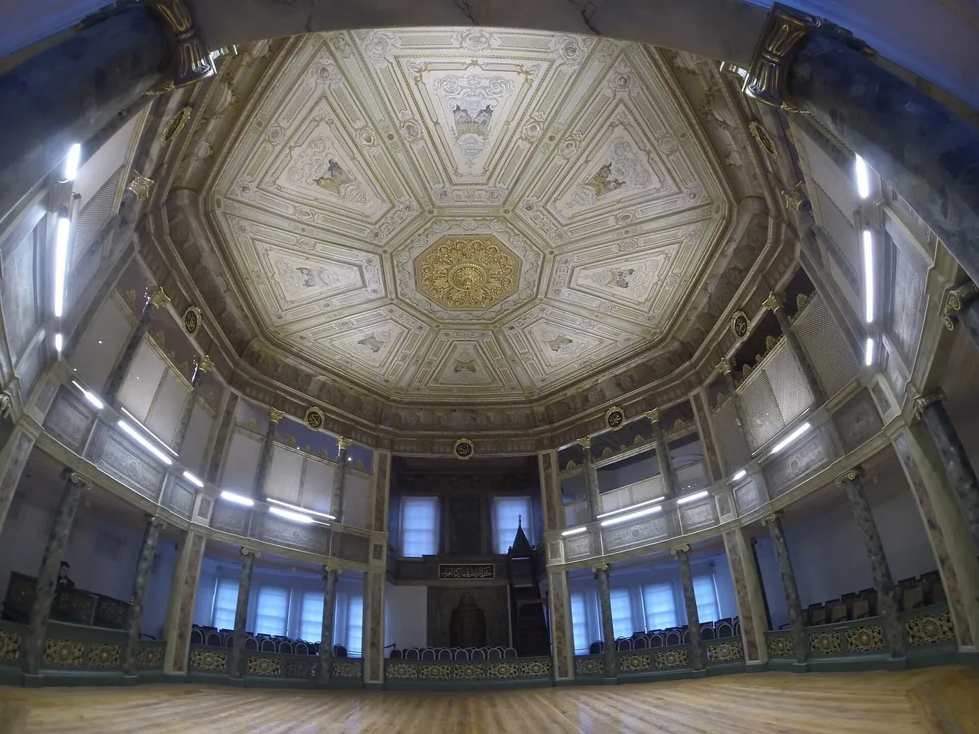 The empty octagonal Sema hall of the Galata Mevlevi Lodge, with a wooden floor, a gallery all round and a painted ceiling