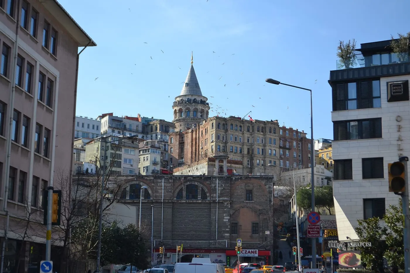 The Galata Tower's conical cap rising above the stacked buildings of Karaköy, with a busy road below