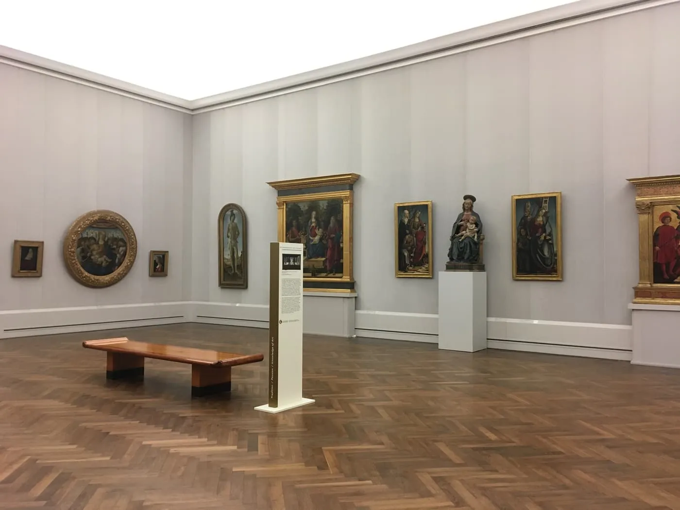 A gallery room in the Gemäldegalerie with Italian Renaissance paintings on pale walls above a herringbone parquet floor