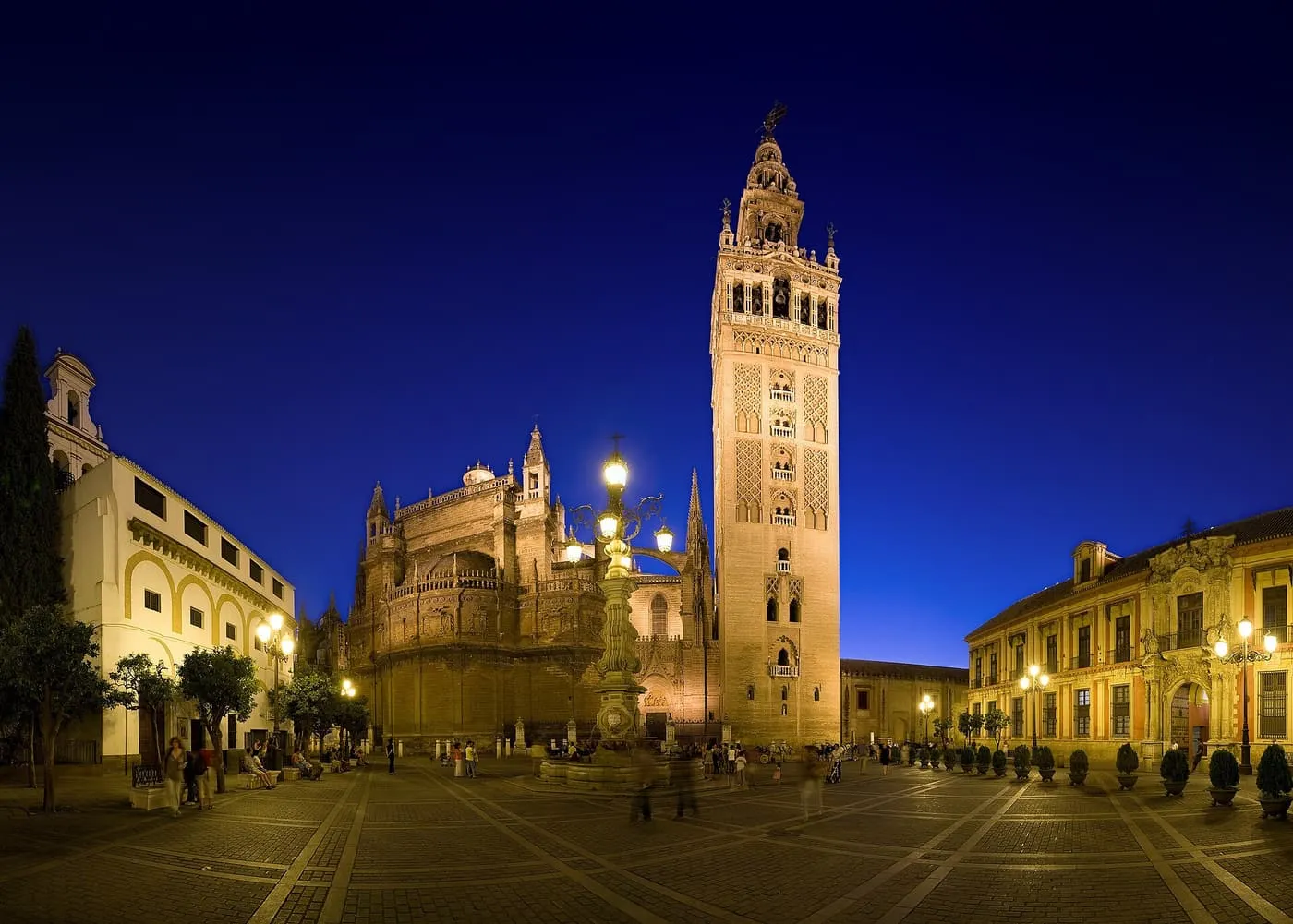 The Giralda and the Cathedral lit at dusk above the Plaza Virgen de los Reyes