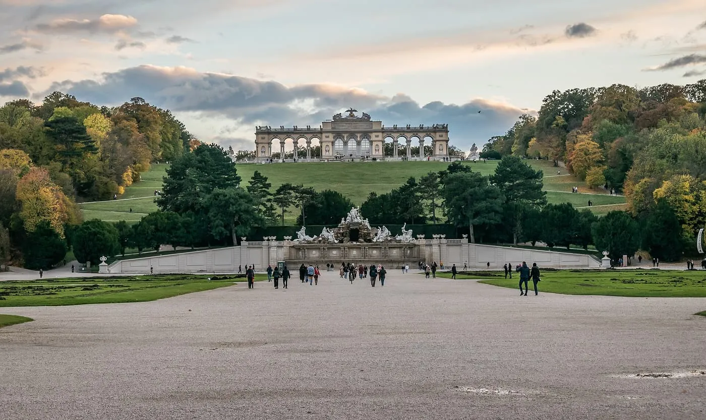 The Gloriette, a long colonnaded pavilion on top of a grassy hill, above the Neptune Fountain at the far end of a wide gravel path