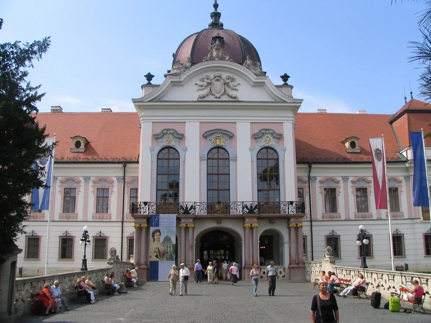 The pink and white Baroque front of the Grassalkovich palace at Gödöllő, with its central dome and a balcony above the entrance