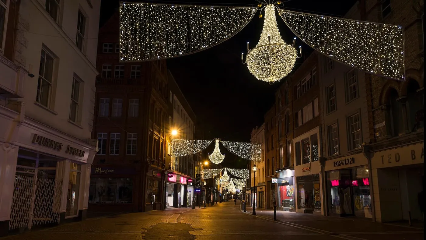 Chandelier-shaped Christmas lights hung across Grafton Street at night, with a curtain of white lights above the shopfronts