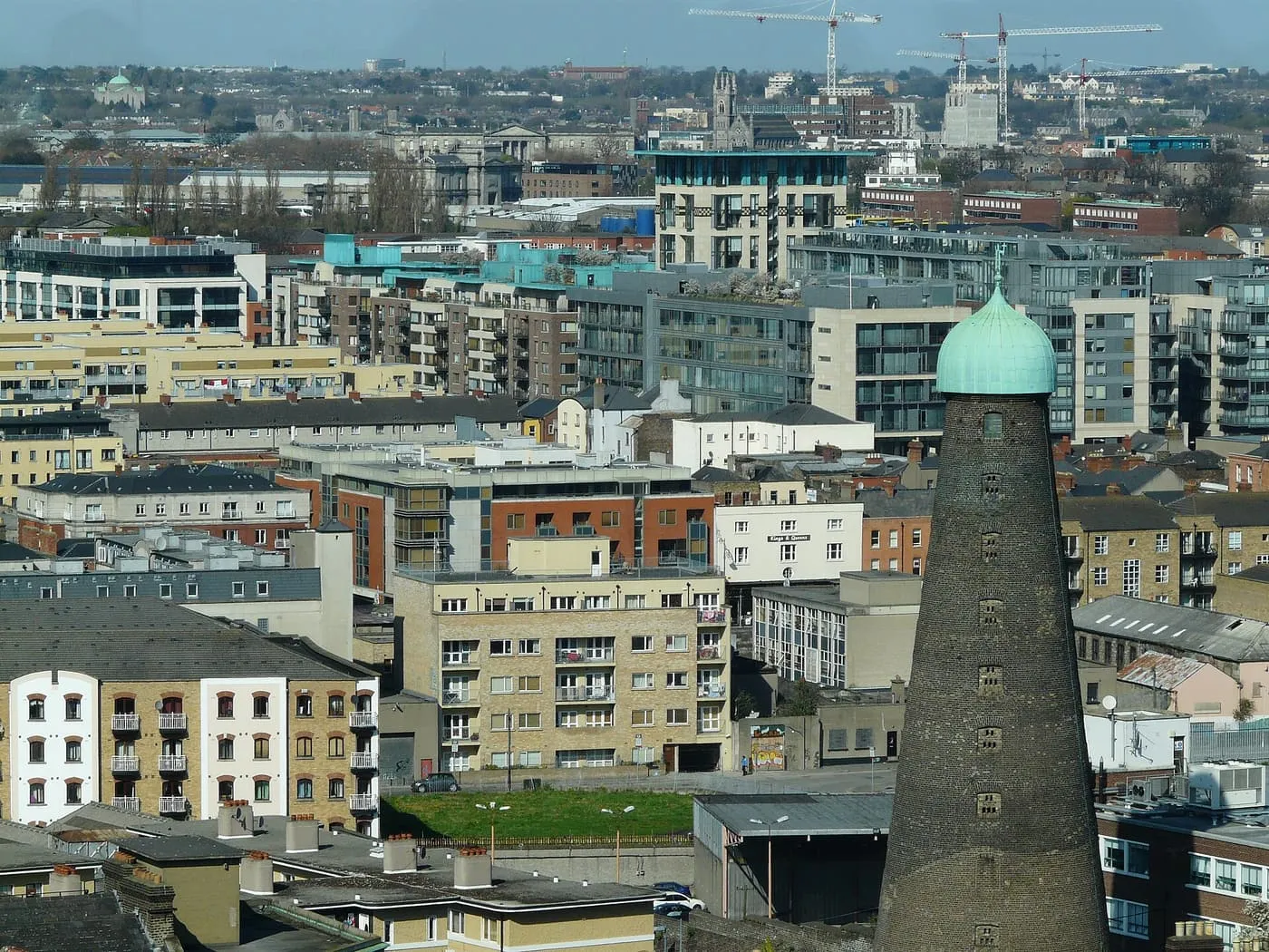 Dublin rooftops and apartment blocks from a high window, with the green-capped round brick tower of St Patrick's windmill on the right