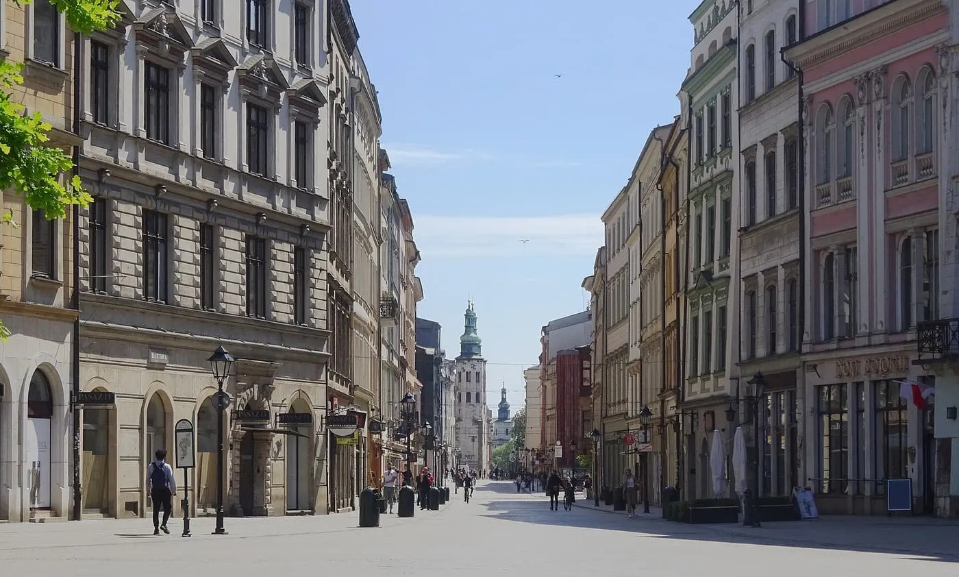 Grodzka Street looking south from the square, a wide paved street of tall townhouses with a church tower in the distance