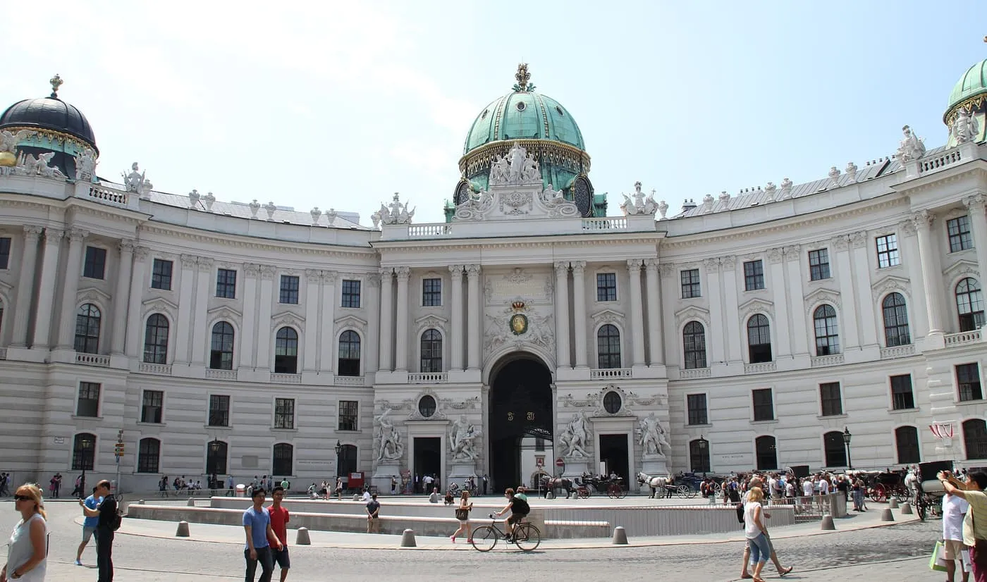 The curved Michaelertor wing of the Hofburg with its green copper dome and arched gateway, seen across Michaelerplatz