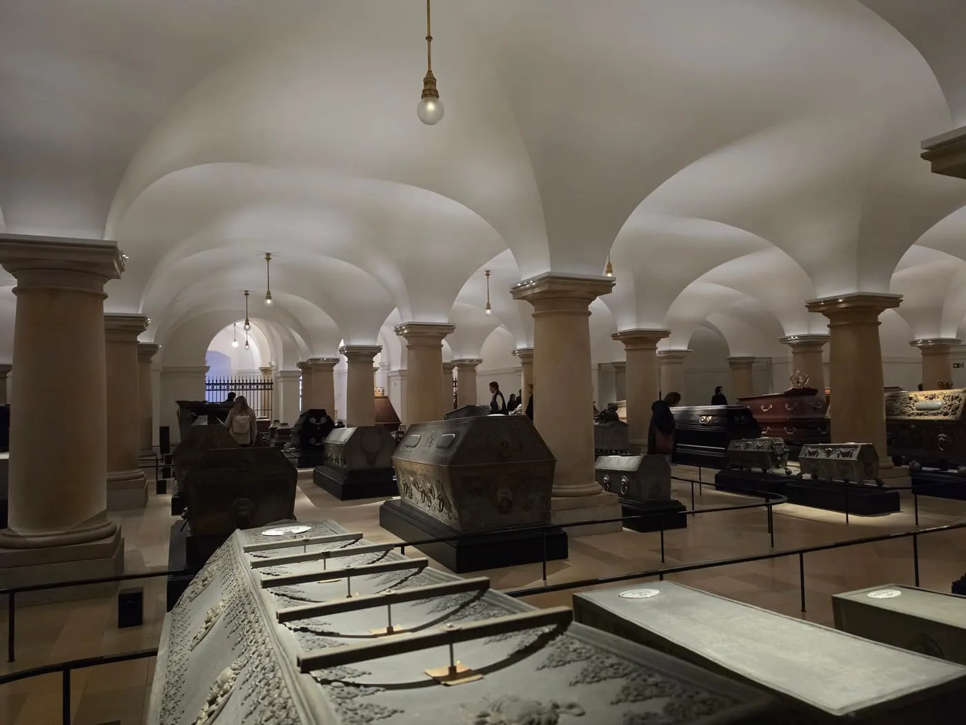 The vaulted Hohenzollern Crypt beneath the cathedral, with stone and metal sarcophagi on low plinths between columns