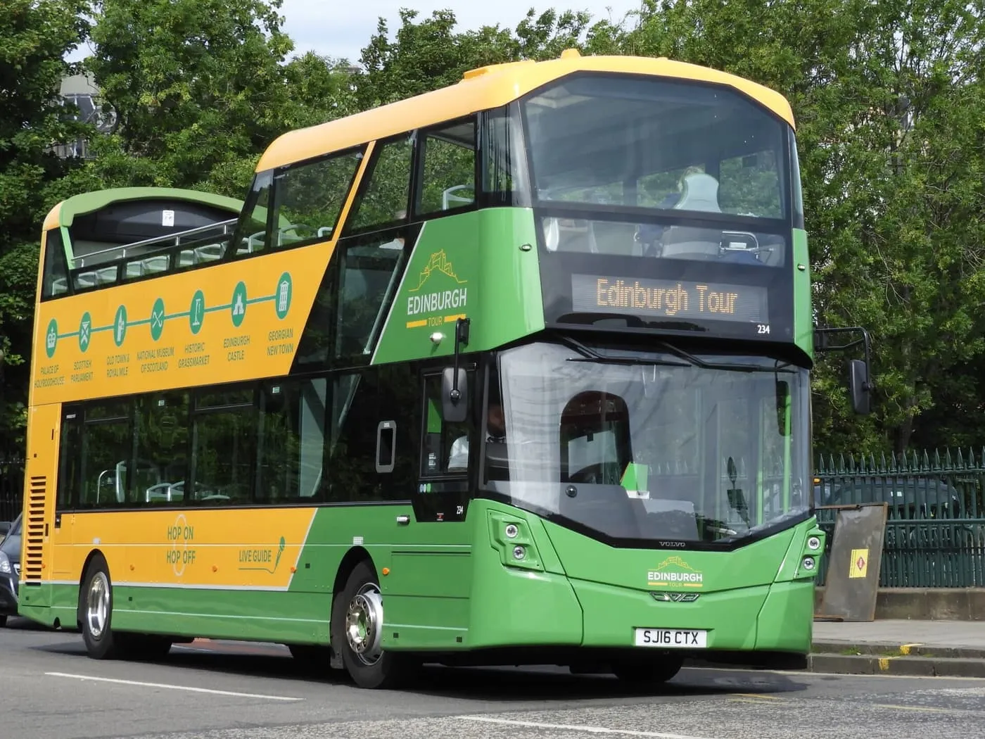 A green and yellow open-top double-decker bus marked Edinburgh Tour