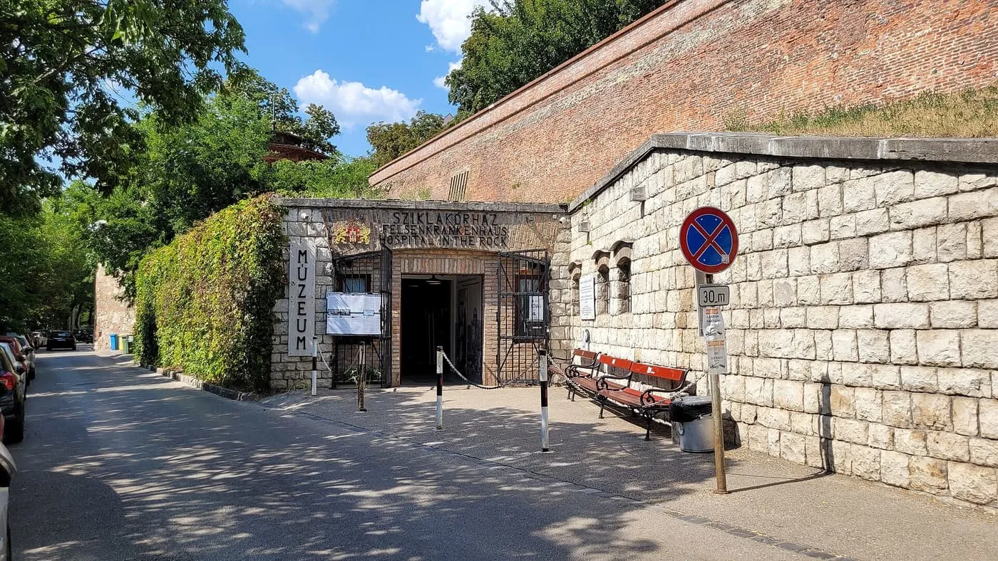 The stone entrance of the Hospital in the Rock museum on Lovas út, under the red-brick wall of the Castle District