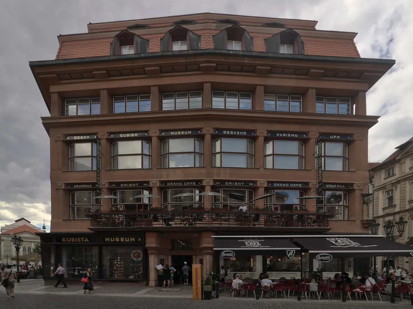 The House at the Black Madonna, a five-storey Cubist building with angular dormers above a ground-floor arcade and a café terrace