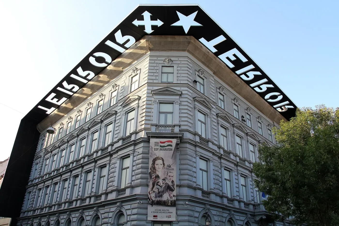 The grey corner building of the House of Terror at Andrássy út 60, with a black blade roof cut with the word TERROR