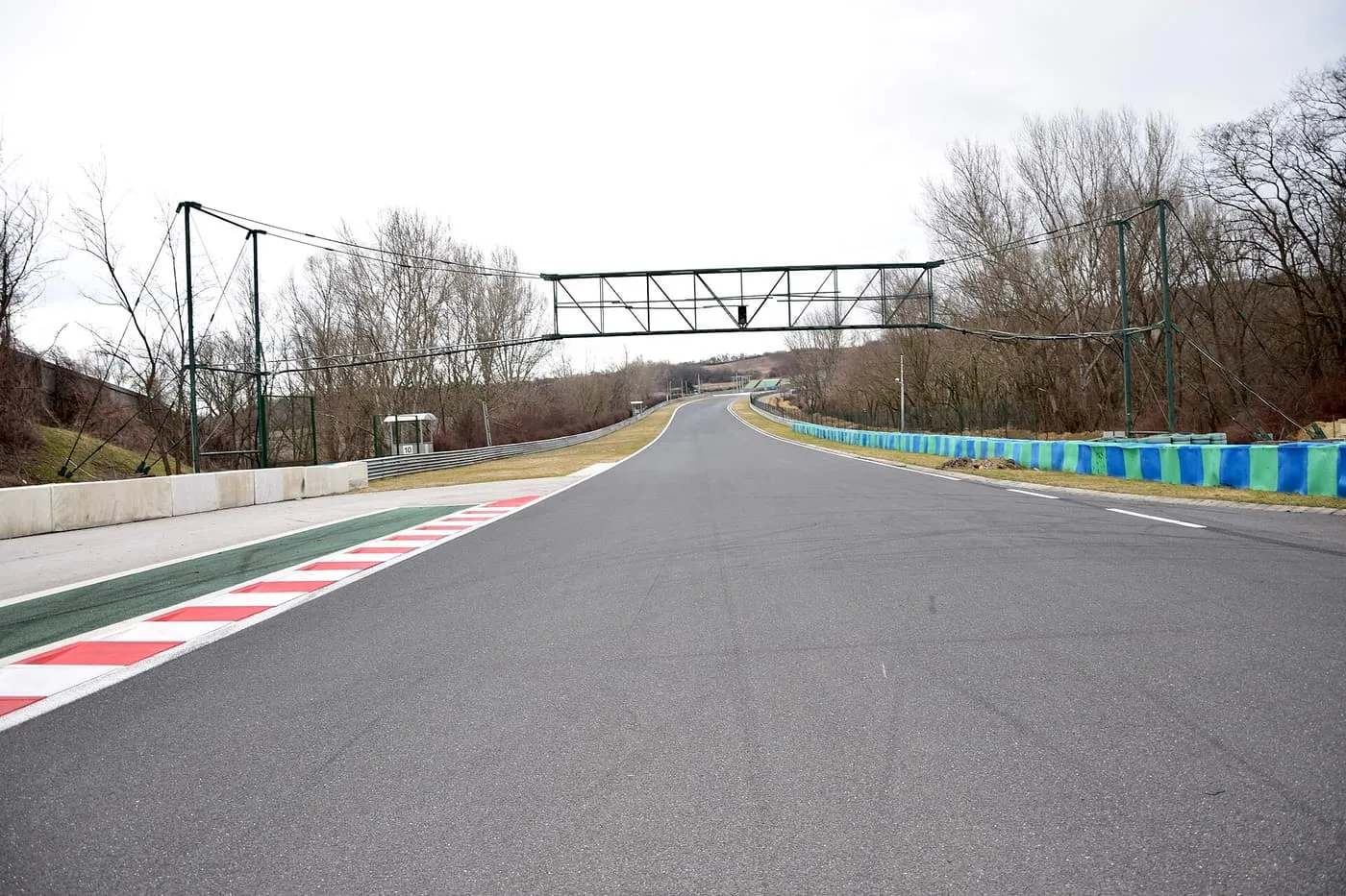 An empty stretch of the Hungaroring motor-racing circuit at Mogyoród, with red-and-white kerbs and a gantry over the track