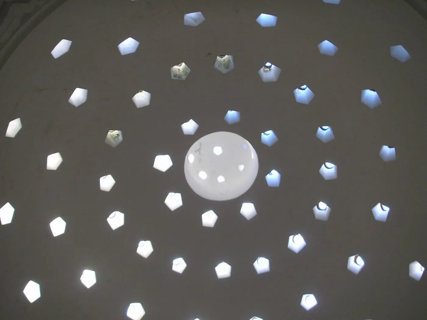 Looking up into a hammam dome pierced with a ring of small glass-covered openings that let in daylight