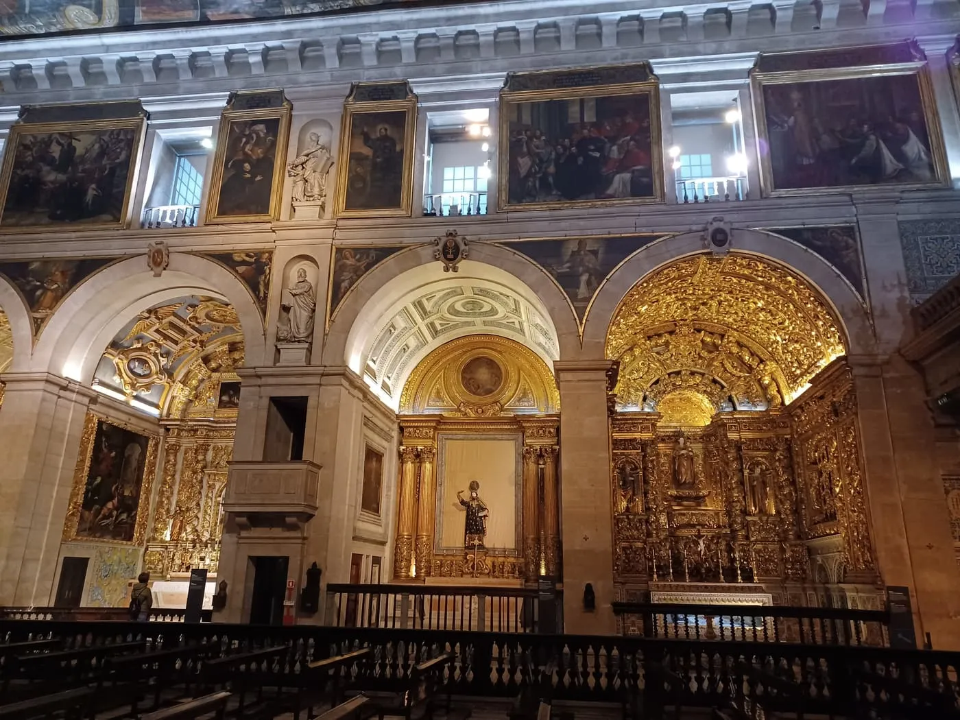 The gilded side chapels of the church of São Roque, with painted panels above the arches and a carved wooden balustrade in front