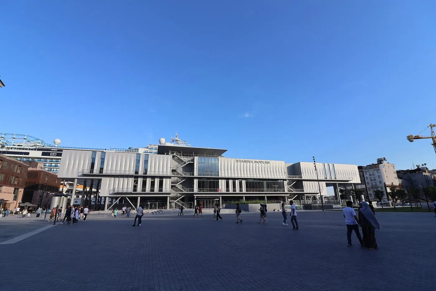 Istanbul Modern, a long low museum building across an open paved square, with a ship moored behind it