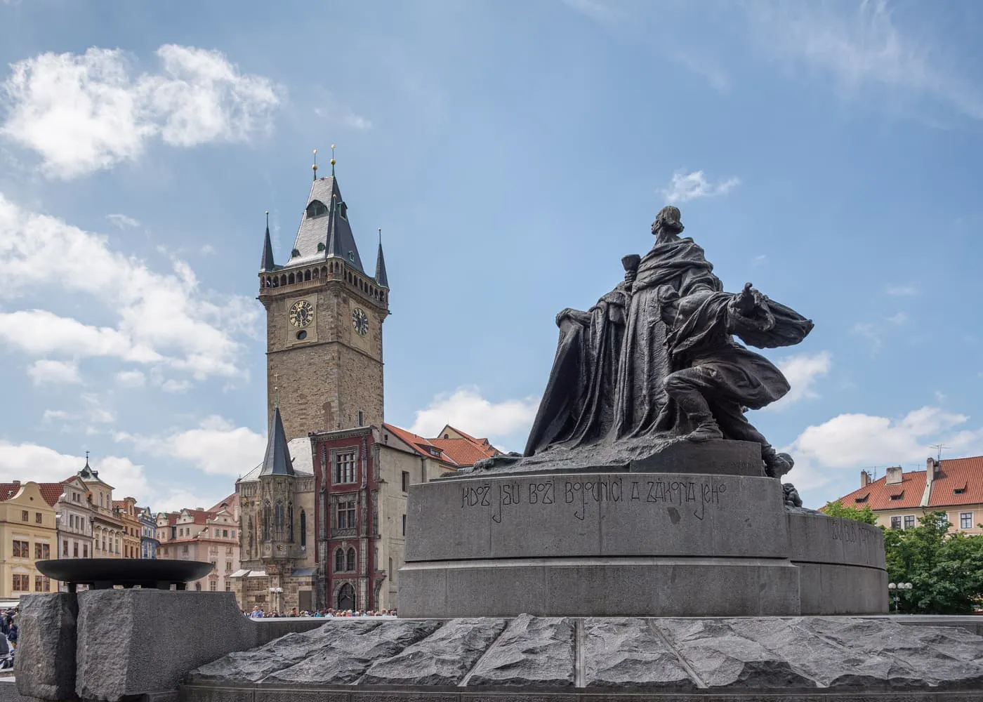 The Jan Hus Memorial on Old Town Square with the Old Town Hall tower and its clock faces behind it