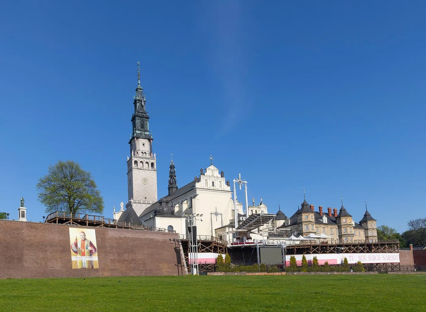 The brick walls of the Jasna Góra monastery across a lawn, with the basilica tower behind