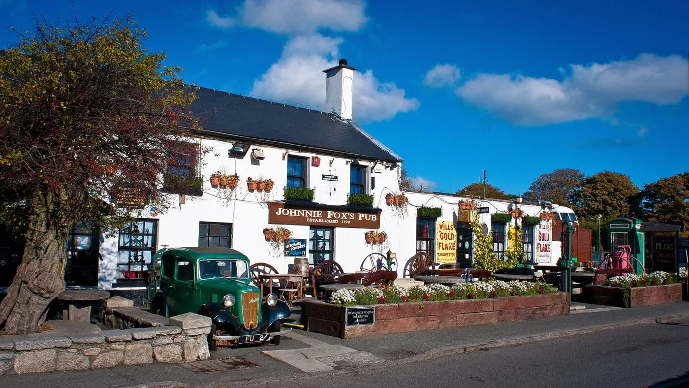 The whitewashed Johnnie Fox's pub at Glencullen under a blue sky, with an old green lorry parked outside