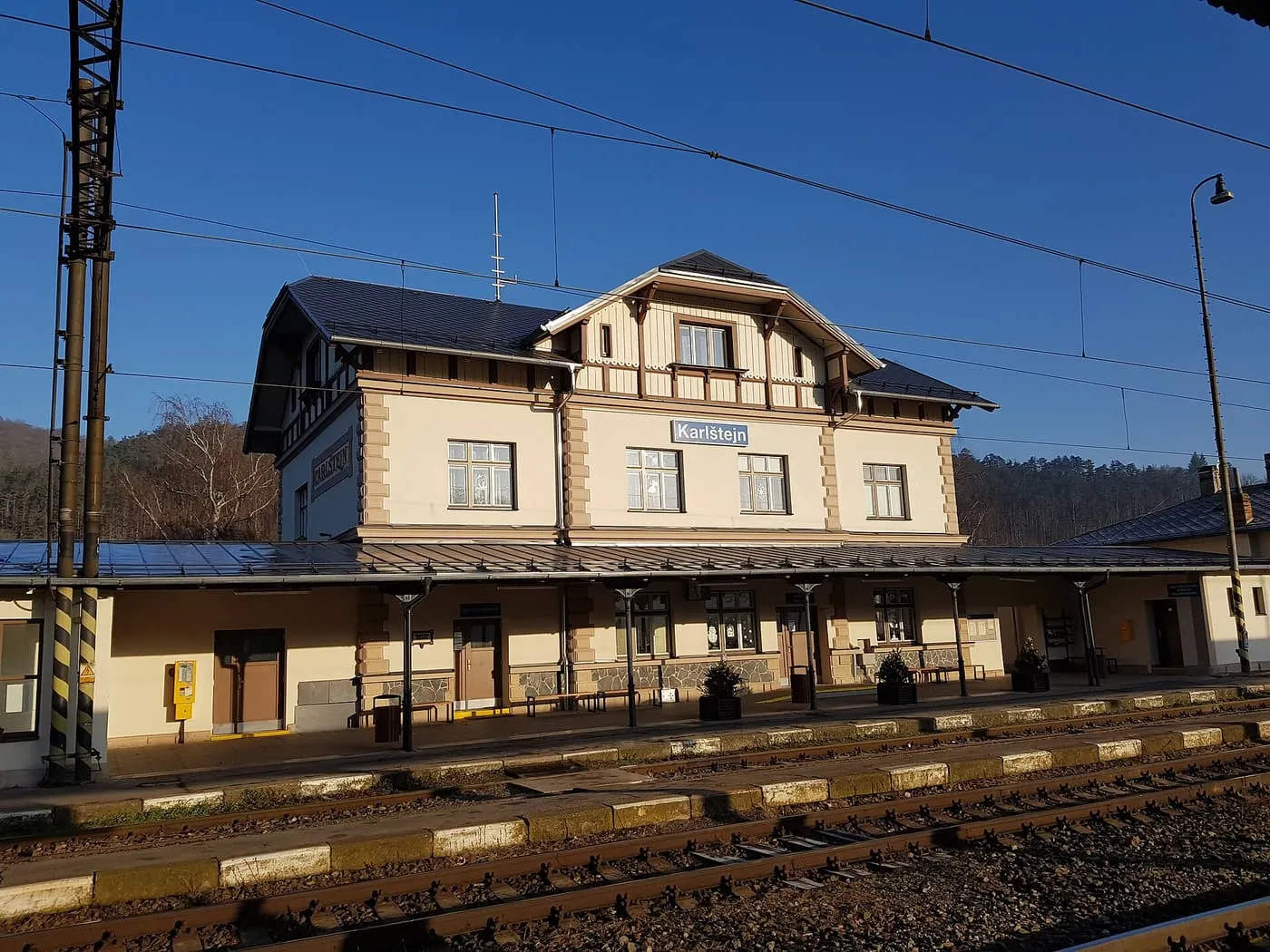 The ochre station building at Karlštejn, with its timber-trimmed gables, seen across the tracks