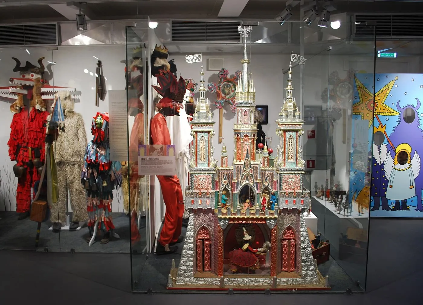 A Kraków szopka in a glass case: a nativity scene built as a many-towered palace in silver foil and red, pink and blue paper