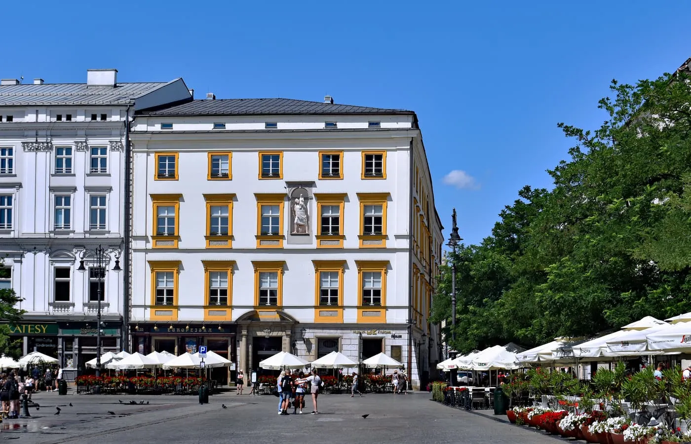The Krzysztofory Palace on the Main Market Square, a white building with yellow window frames and café terraces beneath it